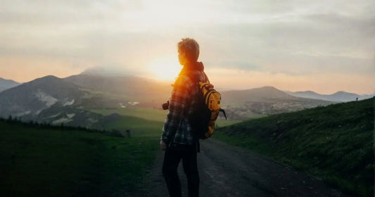 Randonneur avec sac à dos jaune au lever du soleil sur un sentier de montagne